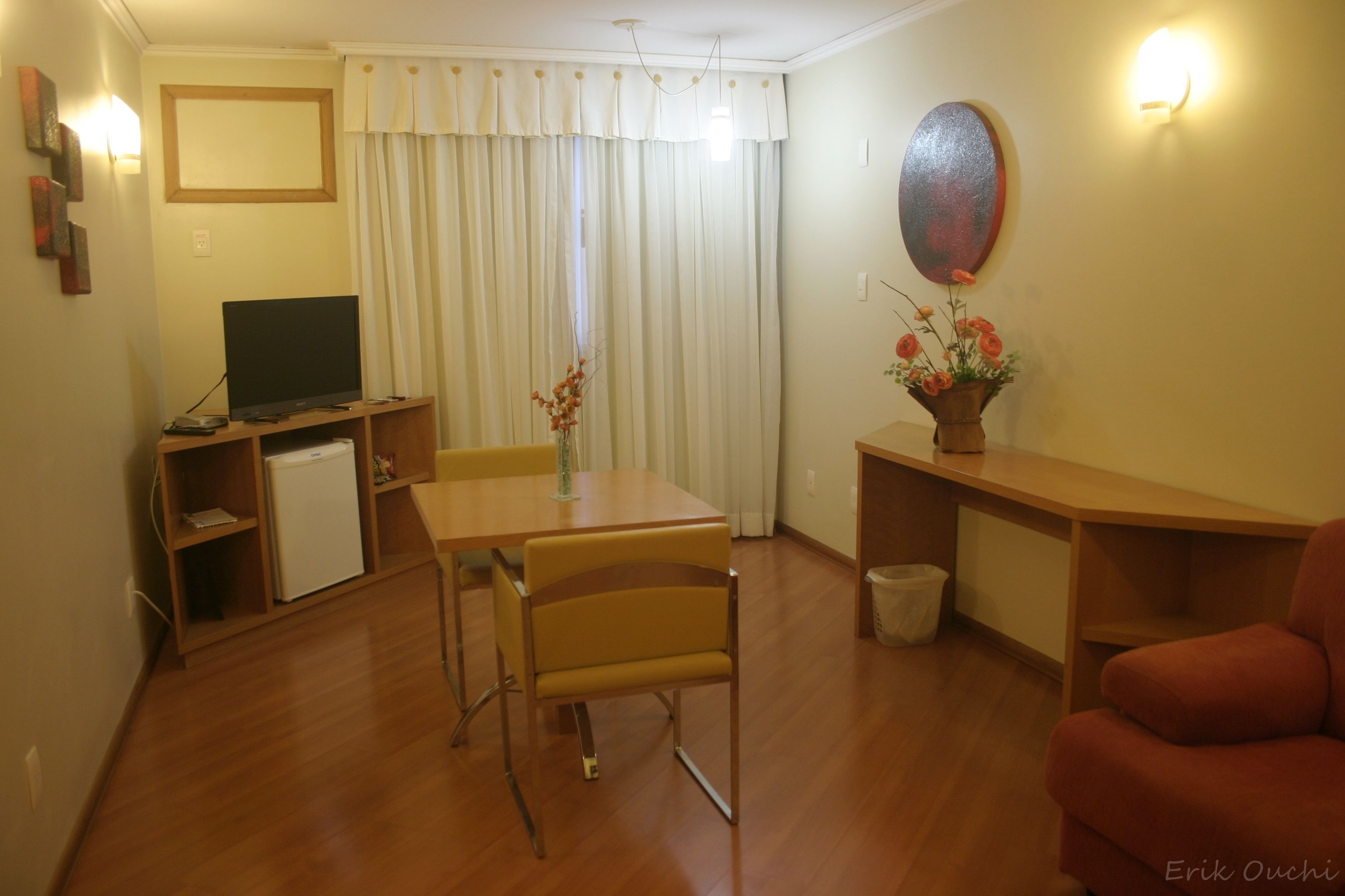 Una sala de estar con televisor, mesa de comedor, sillas, sofá y un mueble bajo.