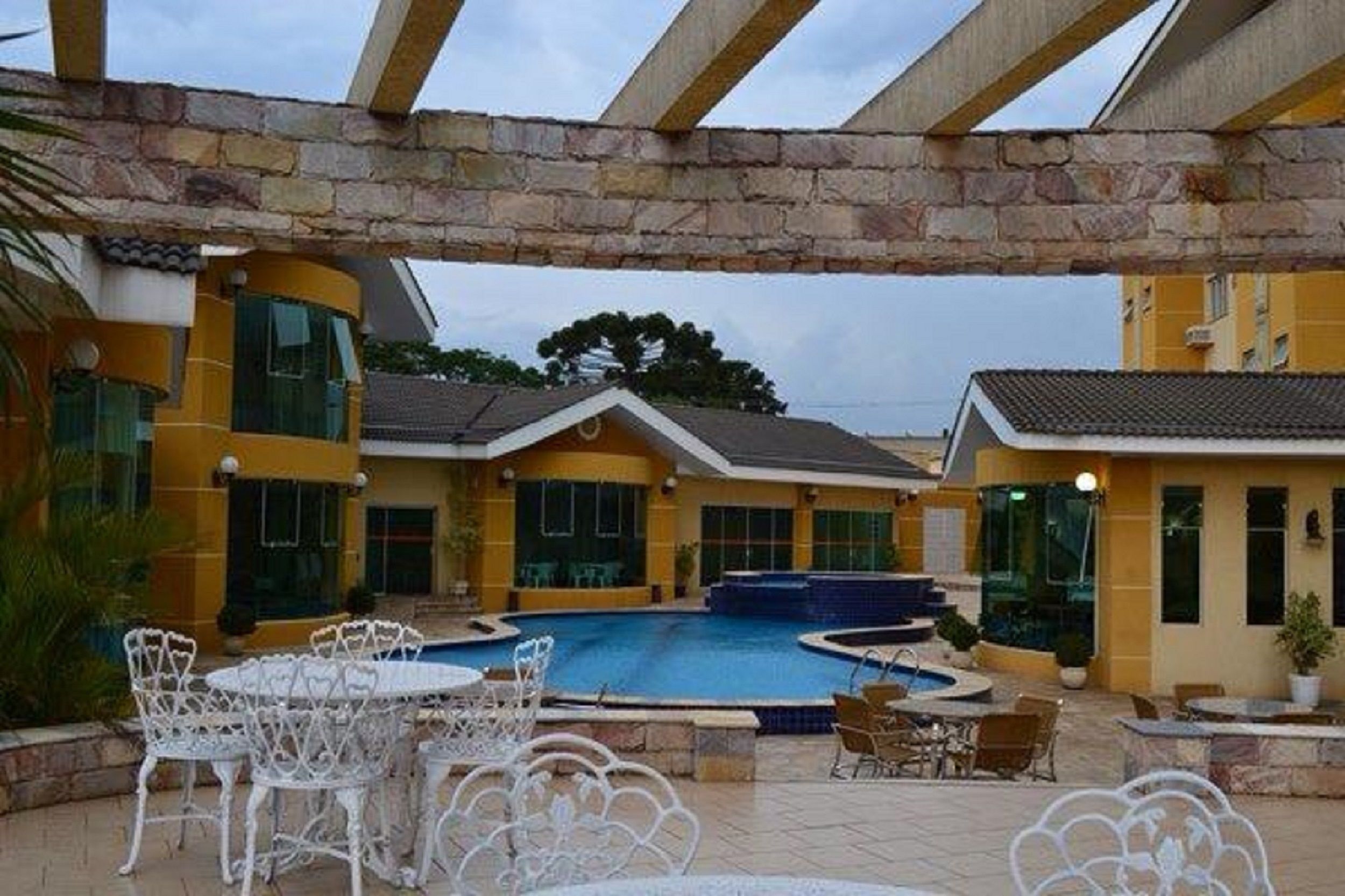 Um pátio com piscina, área de estar externa e arcos de pedra.