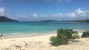 A beach with clear turquoise water, a sandy shore, and distant mountains. - At Home in the Tropics (St. Thomas)