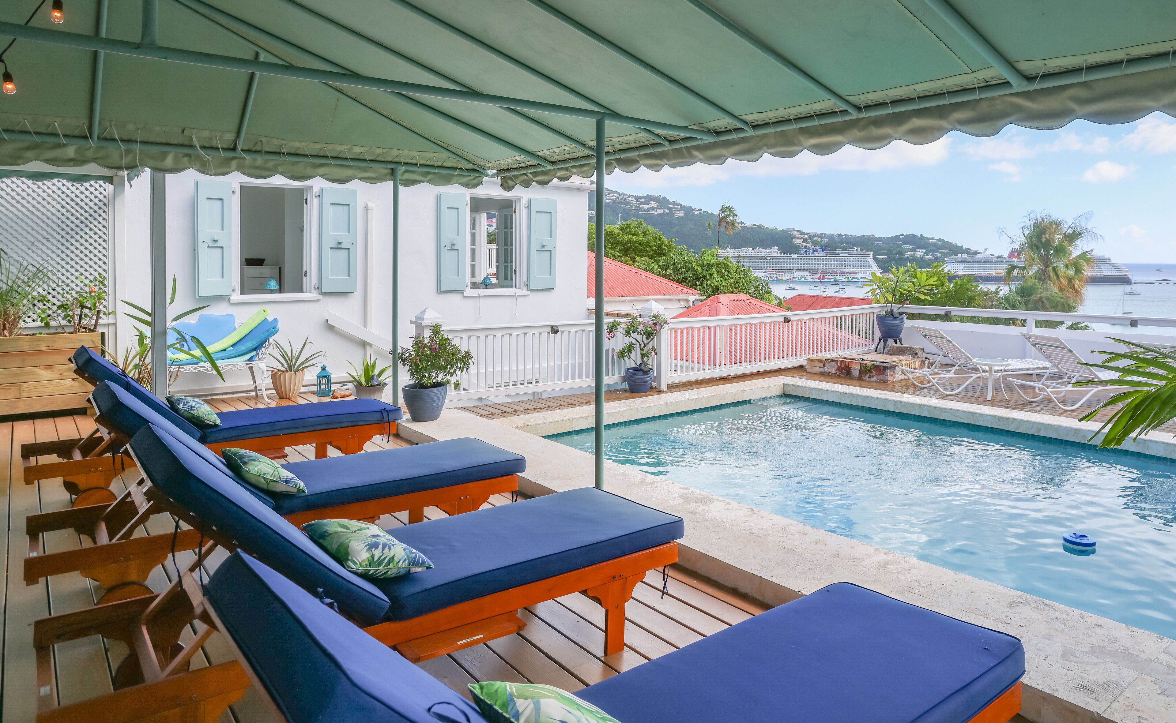 A poolside area with lounge chairs and a view of the sea.