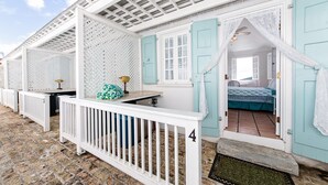 A row of white, cottage-style rooms with blue shutters and a white balcony railing. - At Home in the Tropics (St. Thomas)