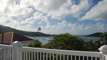 A coastal view with boats, a white railing, and lush greenery.