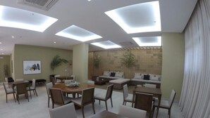 A modern dining area with a round table and chairs, a sofa set, and a brick wall. - London Residencial Design (Niteroi)