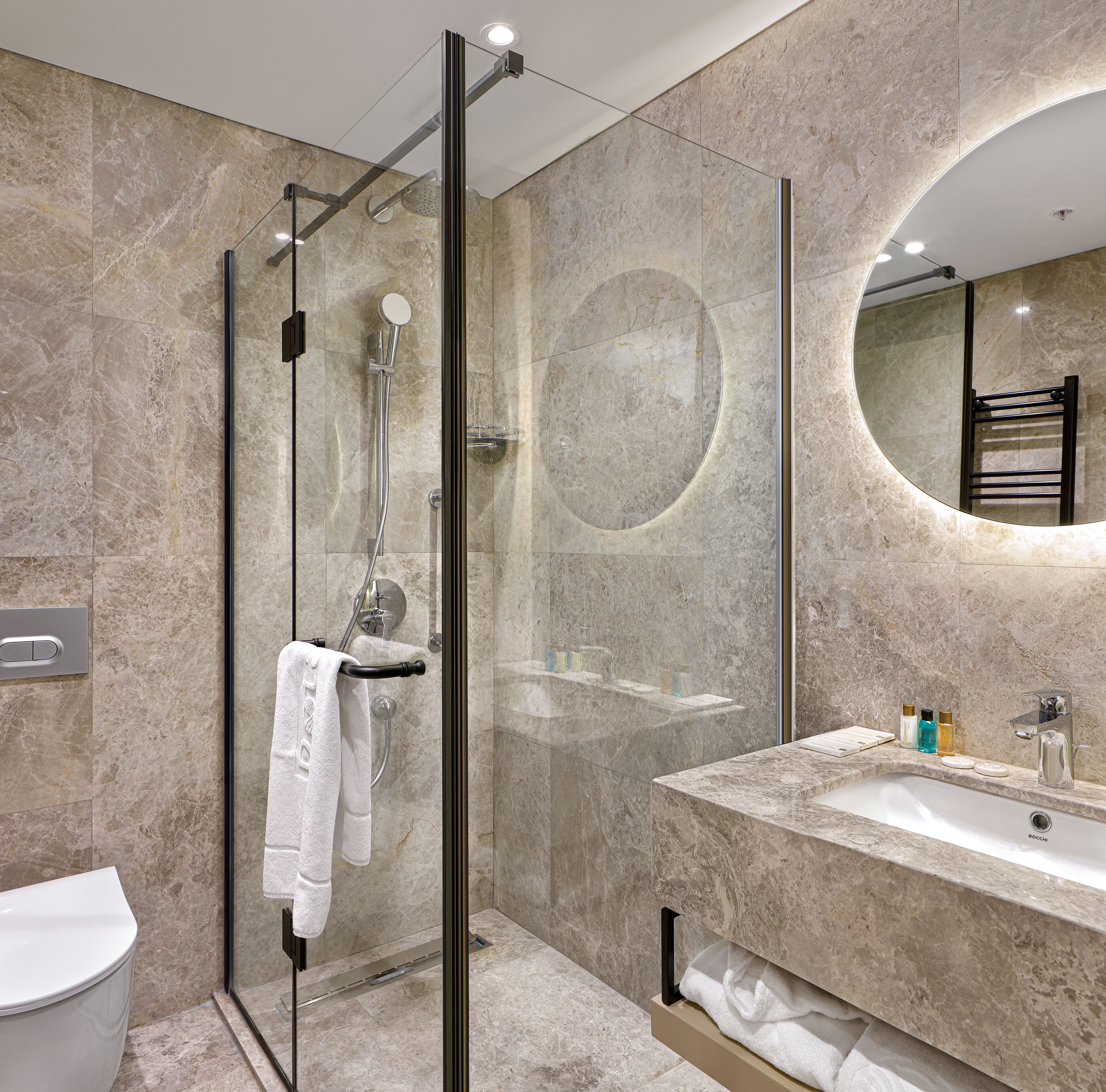 A modern bathroom with a glass-enclosed shower, a marble sink, and a large mirror.