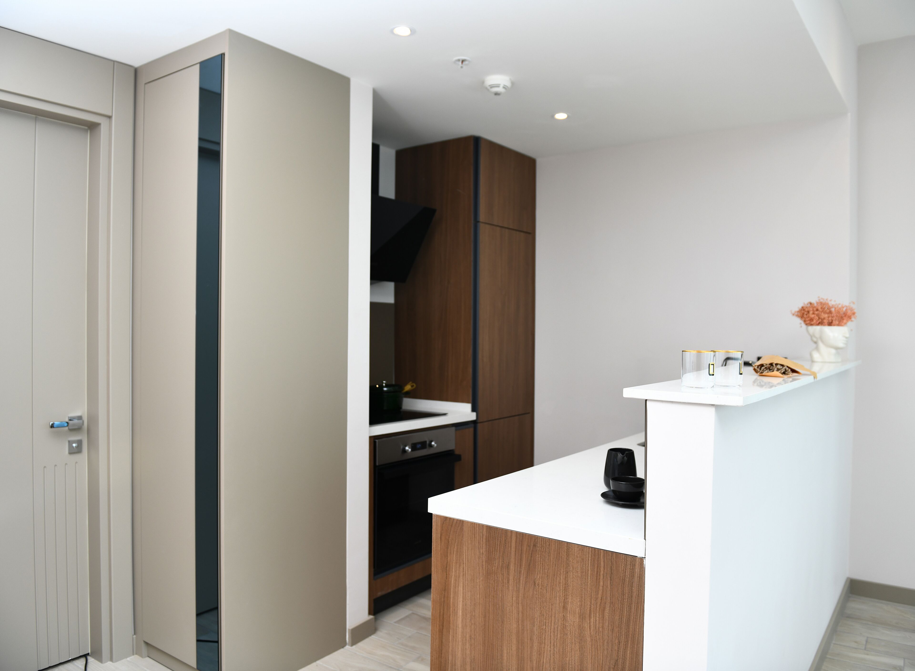 A modern kitchen with a white countertop, wooden cabinets, and a built-in oven.