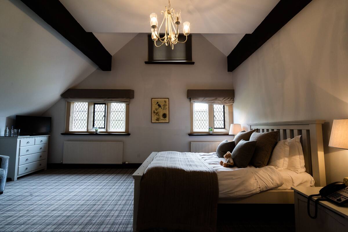 A bedroom with a bed, bedside table, lamp, and a chandelier.