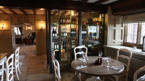 A restaurant with a bar area, wooden beams, and a view of the street. - Weston Hall (Stafford)