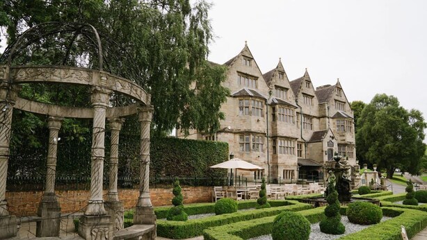 A historic building with a formal garden, including a gazebo, neatly trimmed hedges, and a statue. - Weston Hall (Stafford)