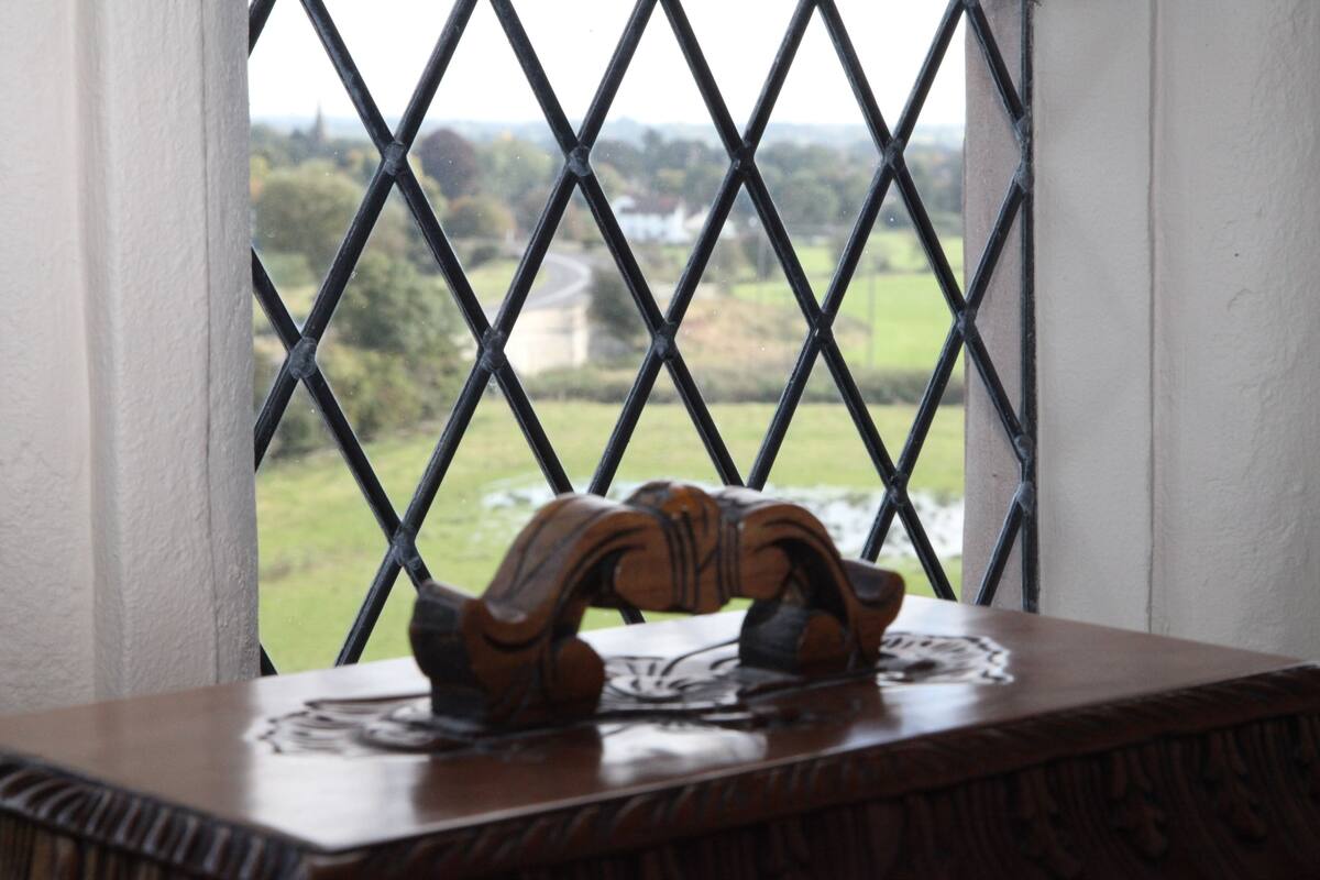 A wooden table with a carved design, positioned in front of a window with a metal lattice.