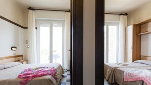 Une chambre d’hôtel avec deux lits, une tête de lit en bois, une table de chevet et une fenêtre avec des rideaux.