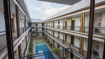 A multi-level hotel with a central swimming pool, balconies, and a modern architectural design.