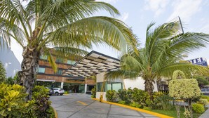 A hotel entrance with a covered walkway, palm trees, and a sign for 'TEL' hotel. - Hotel Andiroba Palace (Tuxtla Gutierrez)