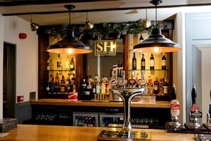 A bar area with a counter, multiple taps, and a variety of bottles. - Saracens Head (Stafford)