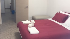 Een hotelkamer met een bed, een stoel en een deur naar een gang.