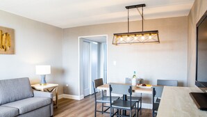 A modern living room with a sofa, dining table, chairs, and a TV.