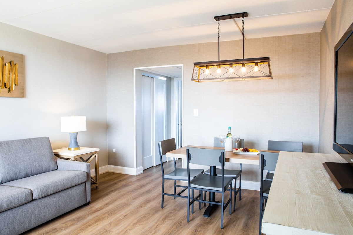 Un salon moderne comprenant un canapé, une table à manger, des chaises et un téléviseur.