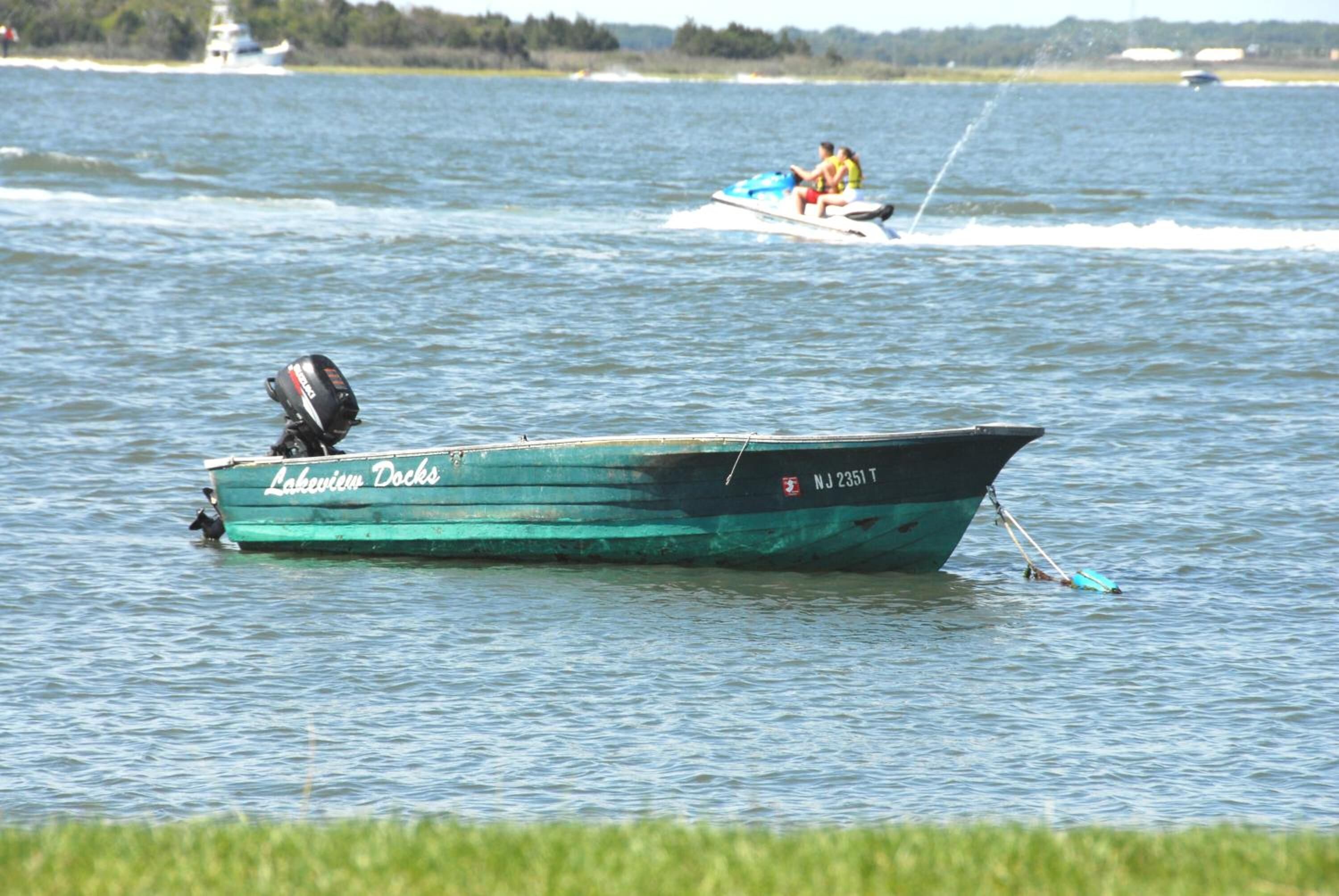 Un bote llamado 'Lakeview Docks' en aguas tranquilas, con estela tras un jet ski.