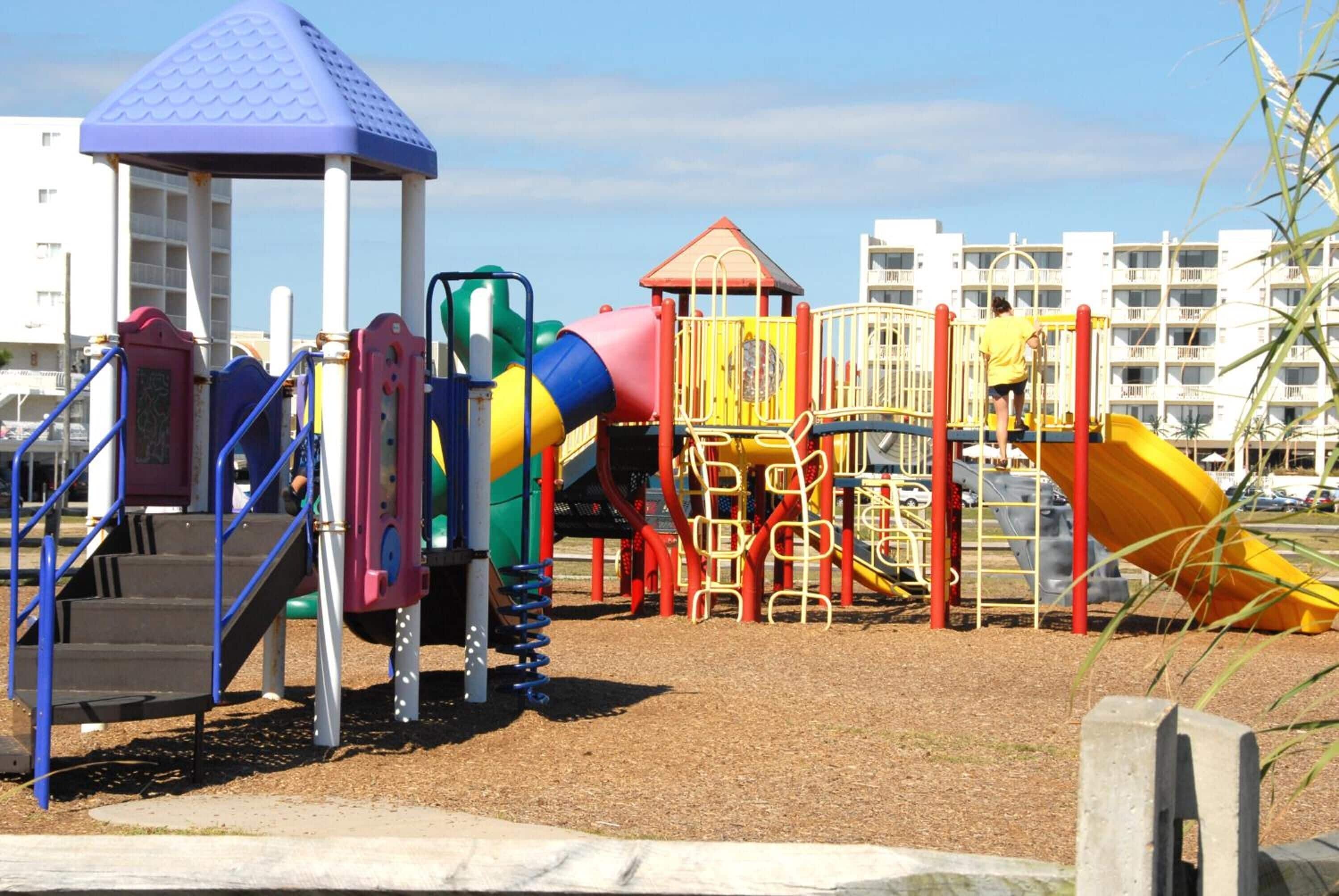 A playground with various play structures including slides, climbing areas, and a small pavilion.