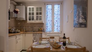 A compact kitchen with white cabinets, a tiled backsplash, and a dining area with a table set for two.
