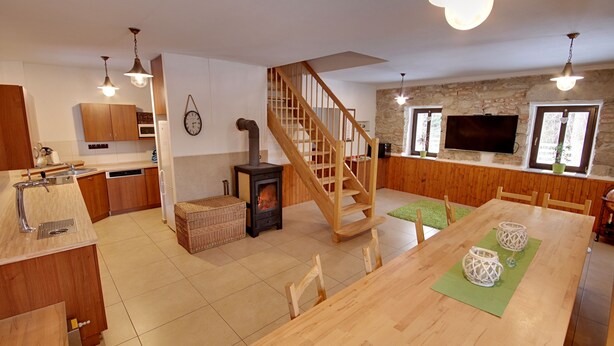 A modern kitchen with wooden cabinets, a built-in oven, and a central island. - Chalupa Jiřík (Volary)