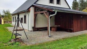A two-story house with a sloped roof, a wooden porch, and a stone-paved driveway. - Chalupa Jiřík (Volary)