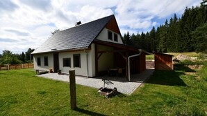 A single-story house with a sloped roof, a covered porch, and a small outdoor seating area. - Chalupa Jiřík (Volary)