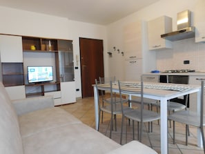 Een moderne keuken met een gasfornuis, witte kasten en een eethoek met een tafel en stoelen.