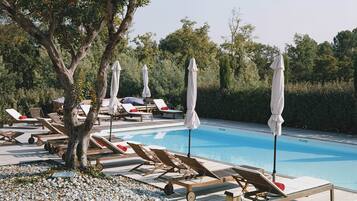 Alberca al aire libre, sombrillas en la alberca y camastros