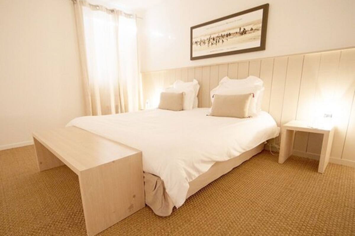 A neatly arranged bedroom with a large bed, a bedside table, and a bench.