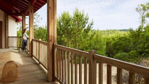 A wooden deck with a red roof, overlooking a forested area. - La Maison de la Prade (Messanges)