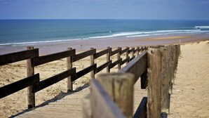 A wooden boardwalk leading to a sandy beach with the ocean in the background. - La Maison de la Prade (Messanges)