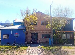 Un edificio de dos pisos con fachada de ladrillo y pared exterior azul. Un letrero en la pared azul dice "POSADA SAN ANTONIO".