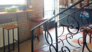 Un interno moderno con pareti in mattoni a vista, una scala in legno e un'area bar con un cartello che riporta la scritta "San Antonio".