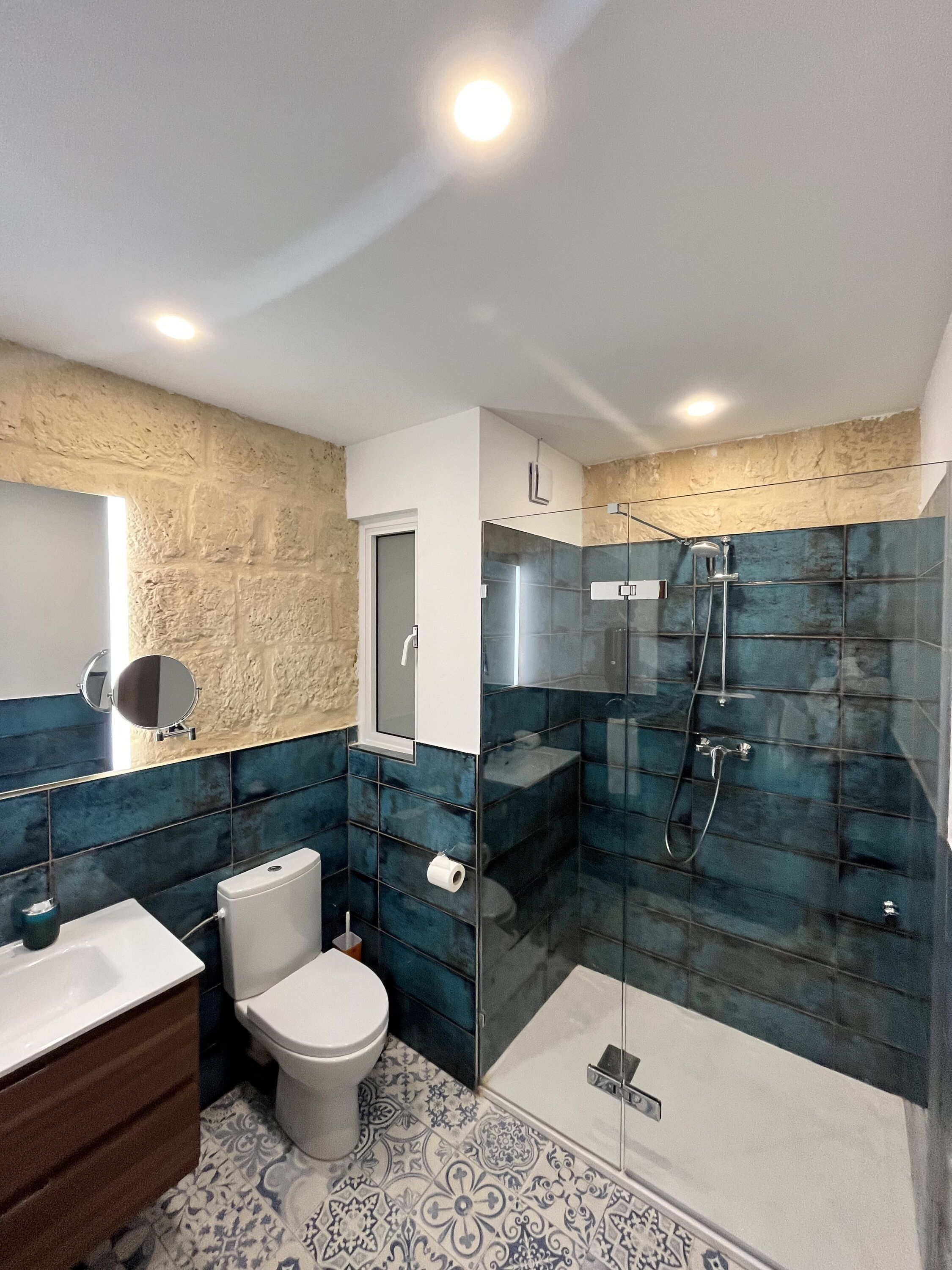 Een moderne badkamer met een douchecabine van glas, een wit toilet en een wastafel met spiegel.