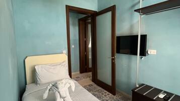 A bedroom with a bed, a bedside lamp, a TV mounted on the wall, and a wardrobe.