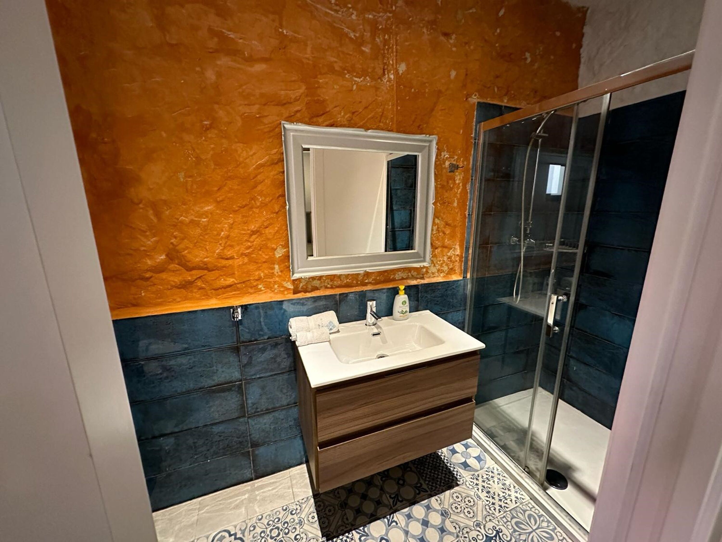 A bathroom with a white sink, a mirror, and a glass shower enclosure.