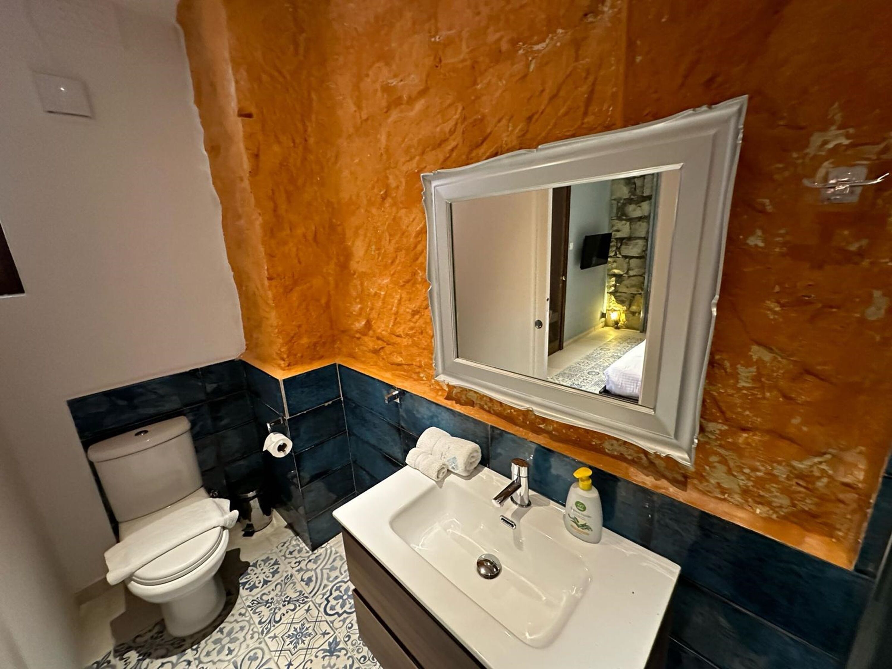 A bathroom with a white sink, a mirror, and a toilet.