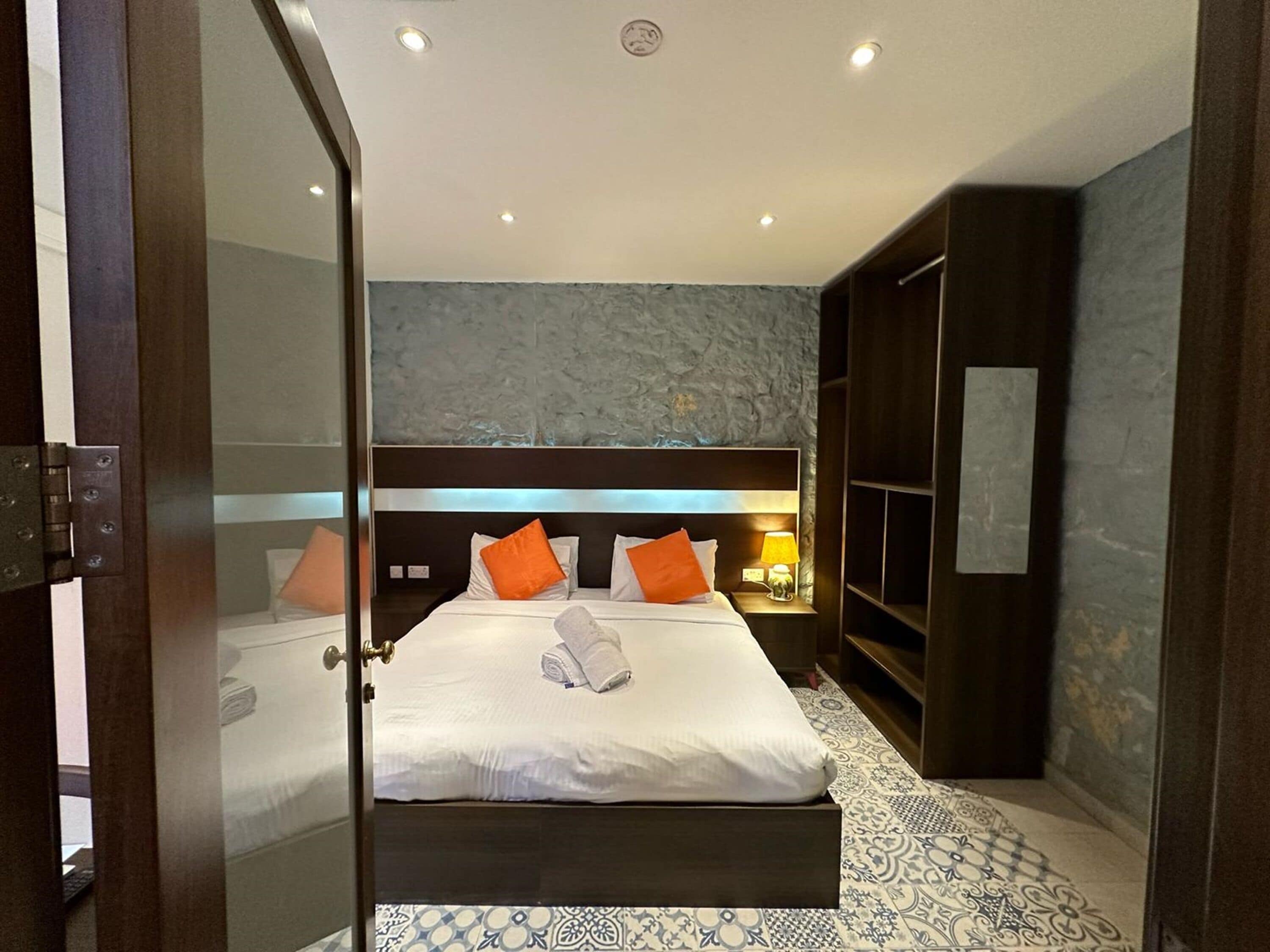 Une chambre d’hôtel avec un grand lit, deux tables de chevet, une armoire et un sol à motifs.