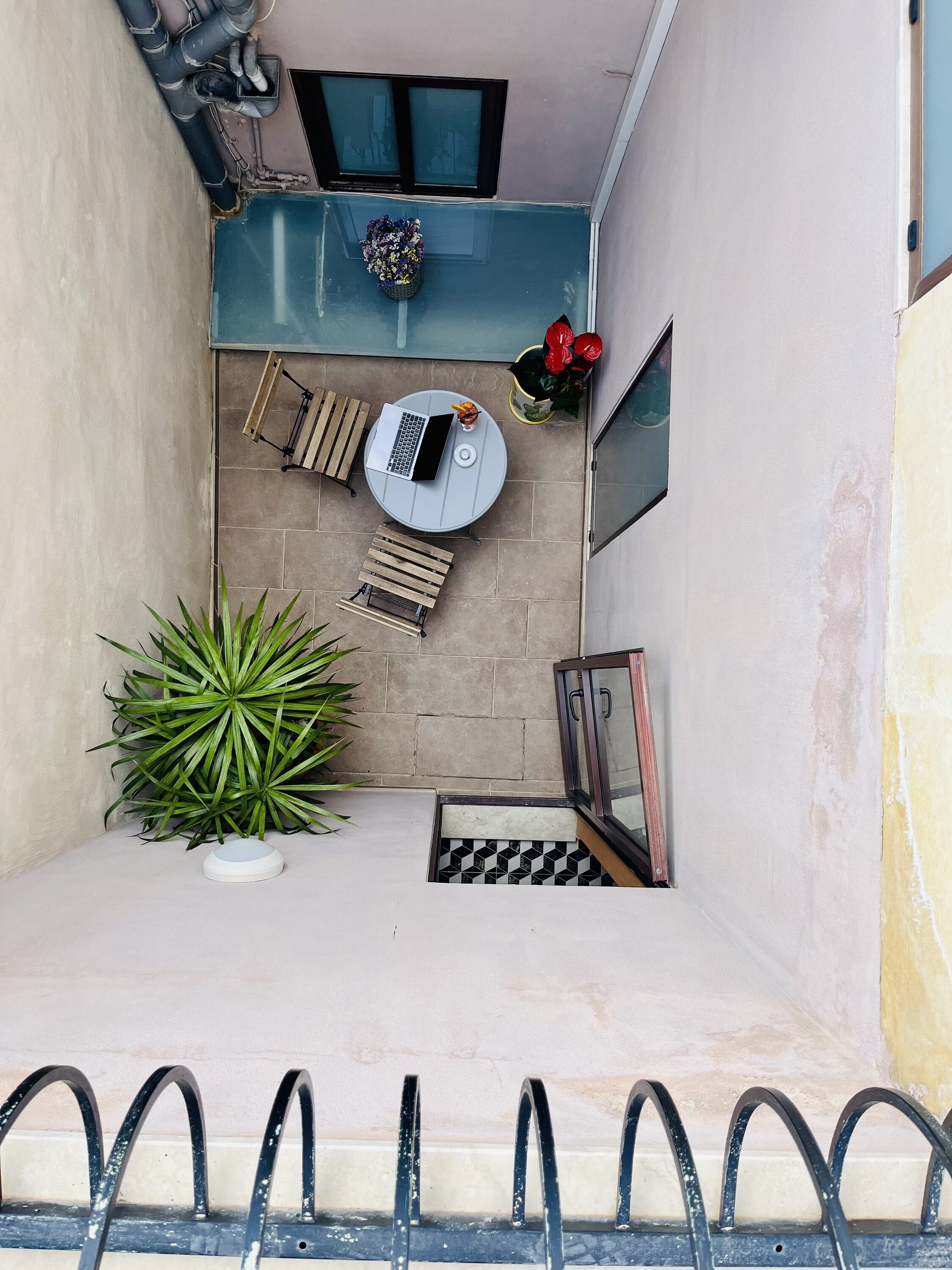 Un piccolo balcone con un tavolo rotondo, una sedia, una pianta in vaso e una finestra.