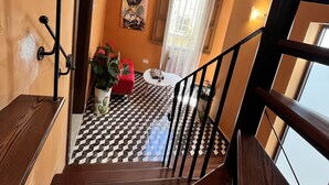 A staircase with a checkered floor leading to a room with a red chair and a table. - MyTravel House (Rabat)