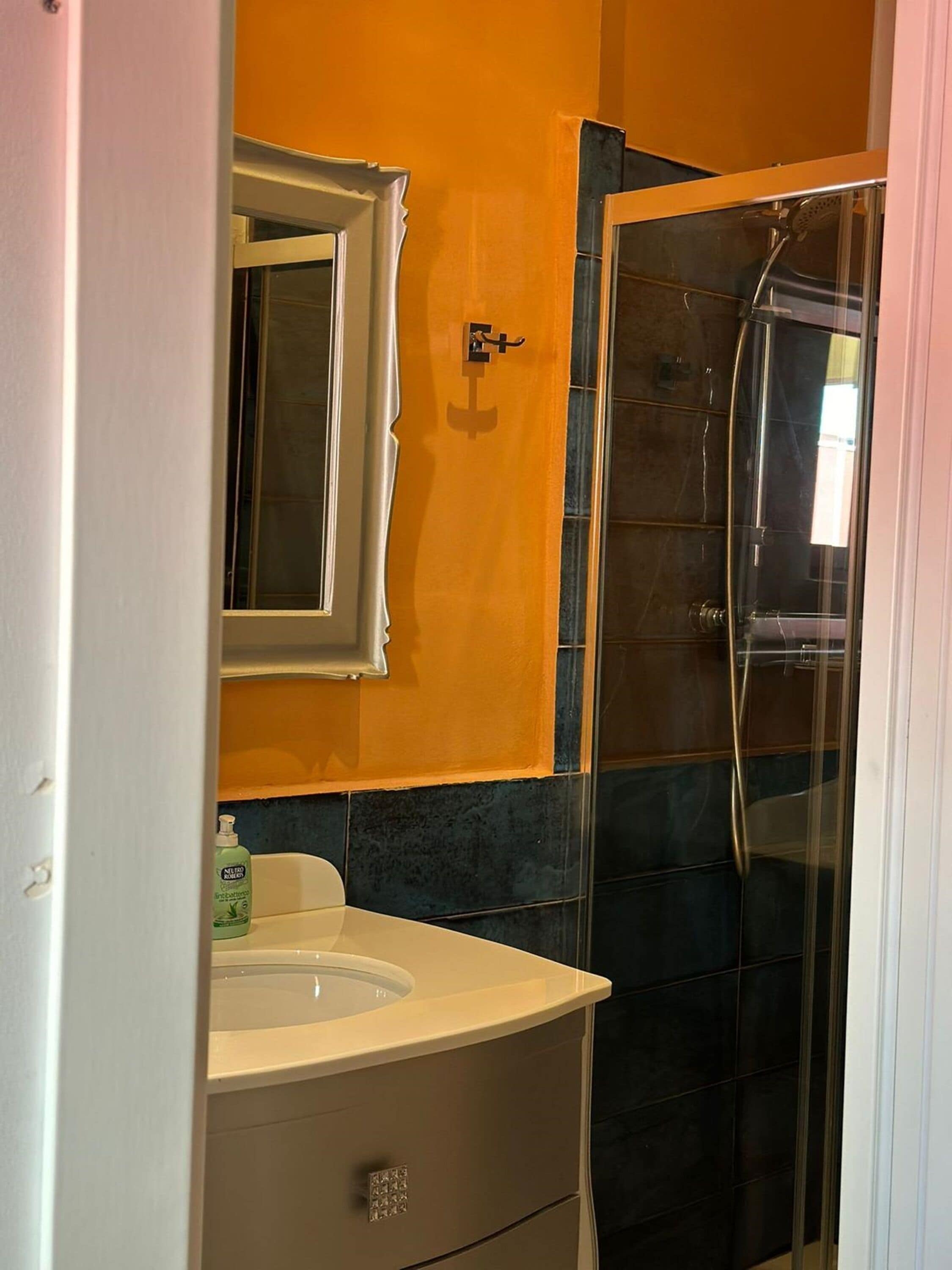 A bathroom with a white sink, a mirror, and a shower enclosure.