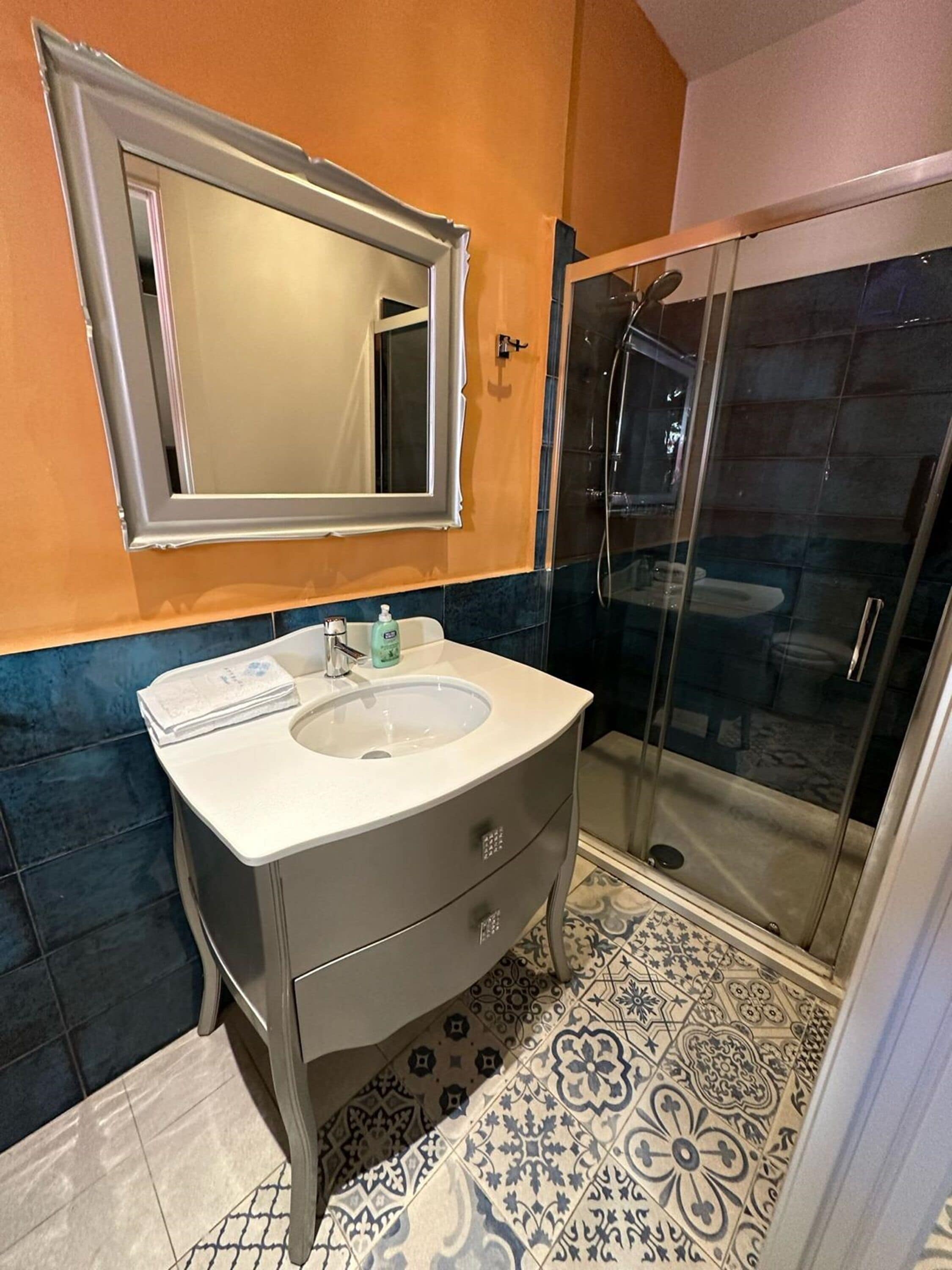 Un baño con lavamanos, espejo y ducha.