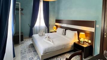A hotel room with a bed, bedside table, lamp, and a blue patterned rug.