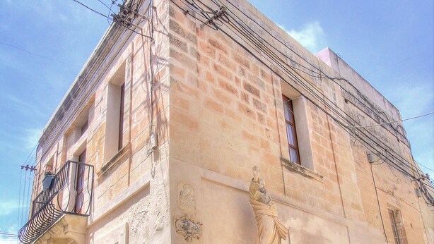 A historic building with a statue, a balcony, and a wooden door. - MyTravel House (Rabat)