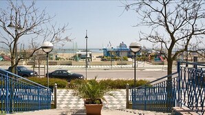 A paved walkway with blue railings leading to a beach area. - Hotel Moja (Cesenatico)