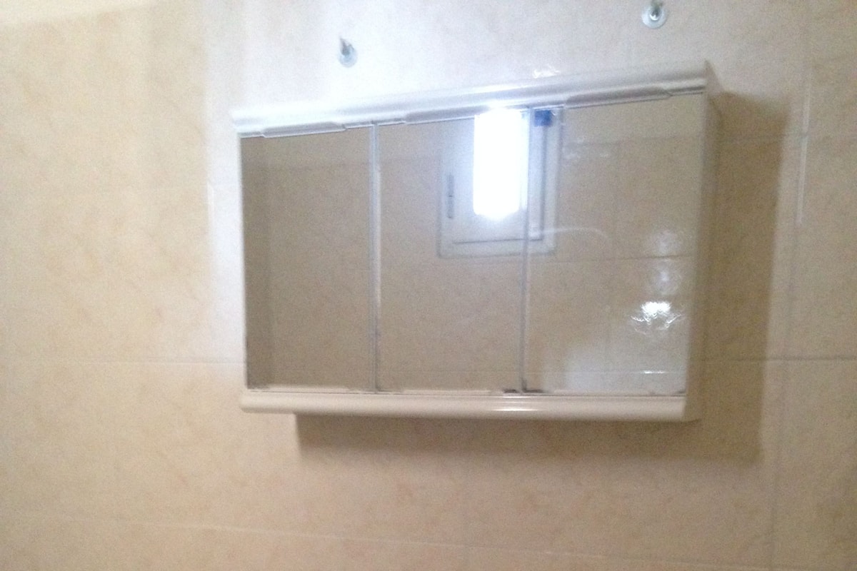 A bathroom with a white sink, a mirror above it, and a small shelf.