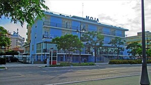 A multi-story building with balconies, a prominent sign, and a parking area. - Hotel Moja (Cesenatico)