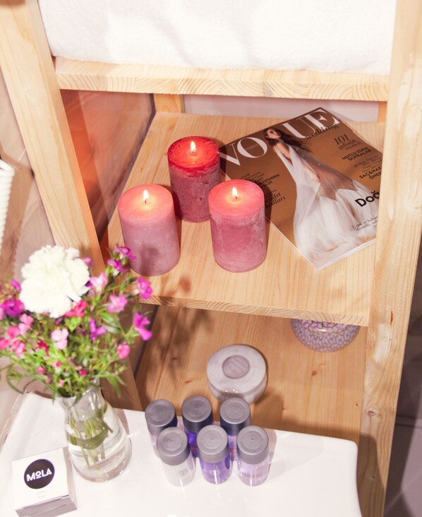 A wooden shelf with candles, a tissue box, and a small vase with flowers. - Hotel MOLA Galata (Istanbul)