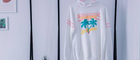 A white hoodie with a graphic design hanging on a black metal rack.