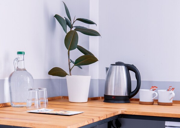 A kitchen counter with a coffee maker, a potted plant, a glass pitcher, and two cups. - Hotel MOLA Galata (Istanbul)
